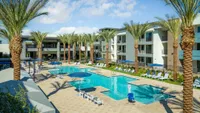 New Apartments Phoenix, AZ - Meritum Sheely Farms - Resort-Style Pool Surrounded By Lounge Chairs And Umbrellas