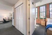 A spacious loft-style bedroom showcases soaring ceilings and expansive windows, flooding the space with natural light. | Watch Factory Lofts | Watch Factory Lofts Apartments