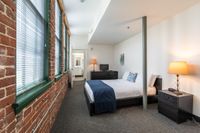 White walls contrast with windowed exposed brick walls in bedrooms at Watch Factory Lofts apartments in Waltham, MA.| Watch Factory Lofts | Watch Factory Lofts Apartments