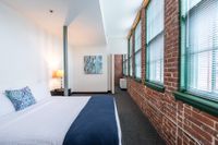 Bedroom with pillar and exposed brick wall at Watch Factory Lofts apartments in Waltham, MA.| Watch Factory Lofts | Watch Factory Lofts Apartments