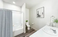 Bright and stylish bathroom featuring a white bathtub with a gray curtain, modern vanity, and chic decor elements.