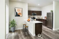 Sleek kitchen with dark cabinets, stainless steel appliances, and an island with bar stools.