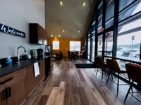 Inviting community lounge with modern decor, including a kitchenette, seating area, and large windows.