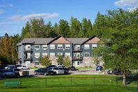 Scenic view of a modern three-story apartment building surrounded by lush greenery.