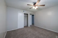 Inviting bedroom with plush carpet, ceiling fan, and ample closet space.