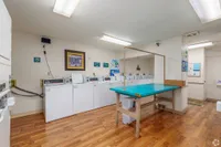 Inviting communal laundry room with modern washers, hardwood floors, and a convenient folding station.