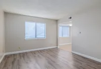 Bright and inviting living area with large window, modern wood flooring, and neutral wall tones.