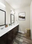 Exquisite bathroom with dual sinks, elegant dark wood cabinetry, and modern decor, showcasing contemporary art and ambient lighting.