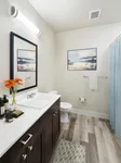 Elegant bathroom with modern fixtures, wooden vanity, stylish wall art, and bright flowers for a fresh ambiance.