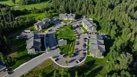 Scenic aerial view of a charming apartment complex nestled in lush greenery, featuring modern buildings, ample parking, and vibrant landscapes.