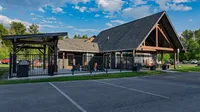 Charming community center with rustic architecture, outdoor seating area, and vibrant greenery backdrop.