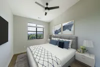 Elegant bedroom with a plush bed and chic decor, featuring large windows with a stunning green view.