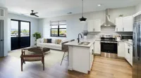 Modern open-concept living area with sleek kitchen, cozy seating, and large windows offering scenic views.