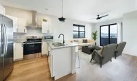 Modern open-concept kitchen and living room with sleek appliances, elegant cabinetry, and a luminous seating area with large windows offering scenic views.