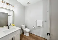 Modern bathroom showcasing elegant fixtures, a sleek white vanity, warm wood flooring, and soft ambient lighting.