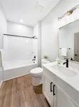Bright and modern bathroom featuring elegant lighting, sleek vanity, and stylish wood flooring.