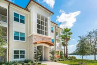 The Marq Highland Park in Westchase Tampa View of Building Exterior, Showing Private Patios and Balconies, Landscape, and Nearby Lake at The Marq Highland Park Apartments