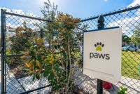 Marq Highland Park Dog Park View of Dog Park, Showing Fenced-In Dog Park and Paws Signage at The Marq Highland Park Apartments in Westchase Tampa