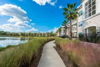 The Marq Highland Park Walking Trail in Westchase Tampa View of Walking Trail, Showing Walking Path, Lake to the Left, and Building Exterior to the Right at The Marq Highland Park Apartments