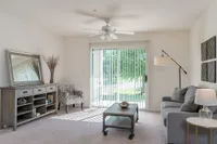 Living Room and Patio View of Furnished Living Room, Showing Couch, Carpet, Ceiling Fan, Sliding Glass Door and Décor at Clearview Apartments