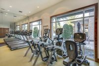 Marq Highland Park Cardio Machines View of Fitness Center, Showing Treadmills, Ellipticals, and Stationary Bicycle at The Marq Highland Park Apartments in Westchase