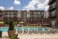 The Melrose Apartments in South Nashville resort-style pool deck Modern apartment complex featuring a serene pool area with lounge chairs and green parasols at The Melrose in South Nashville.