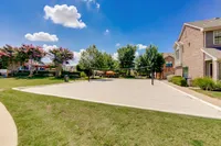 Inviting outdoor sand volleyball court surrounded by lush greenery and beautiful brick buildings, perfect for relaxation and recreation at Enclave on Golden Triangle Apartments.