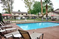 Inviting outdoor pool sundeck at Camelot Aparments in Yuma, AZ with a sparkling pool, surrounded by lounge chairs and lush greenery, perfect for relaxation and enjoyment.