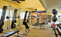 Camelot's modern fitness center with state-of-the-art equipment, vibrant yellow walls, and large mirrors enhancing the spacious feel.