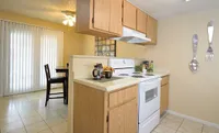 Inviting Camelot Apartment's kitchen with wooden cabinets, modern appliances, and charming dining area, ideal for cozy meals.