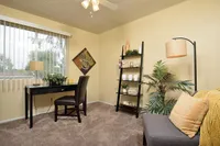 Cozy home office at Camelot in Yuma with a modern desk by a sunlit window, featuring stylish decor and lush indoor plants.