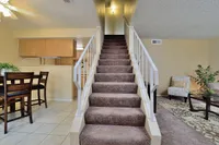 Inviting apartment interior with a stylish staircase leading to an upper floor, featuring an open-plan living space with modern dining area and cozy seating at Camelot Apartments in Yuma, Arizona.