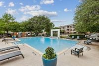 Resort-Style Pool and Sundeck Inviting outdoor pool area at Toscana Valley Ridge Apartments with stylish loungers, lush greenery, and a tranquil waterfall feature surrounded by modern apartment buildings in Lewisville Texas