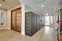 Modern apartment clubhouse at Raveneaux Apartments with sleek Luxer One package lockers and elegant wooden doors, offering a bright and welcoming atmosphere.