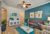 Inviting living room model at Raveneaux Apartments with teal accent wall, stylish decor, and cozy seating area for modern living.