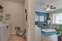 Chic Raveneaux Apartments' apartment interior featuring a cozy laundry nook and a stylish living room with modern decor, abundant natural light, and elegant furnishings.