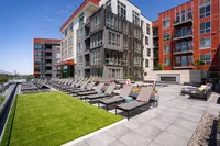 Pool Deck Exterior view of Sugarmont Apartments and Townhomes with vibrant facades and expansive outdoor terrace featuring sun loungers and green lawn, perfect for relaxation.