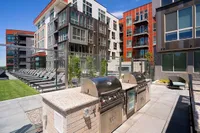 Grills and Outdoor Area Modern apartment complex, Sugarmont Apartments, with vibrant architecture featuring spacious outdoor patio with stainless steel grills and comfortable seating area.