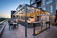 Outdoor Entertaining Area Elegant rooftop patio at Sugarmont in Salt Lake City, UT with modern pergola, sparkling string lights, and ample seating, offering stunning sunset views for social gatherings.