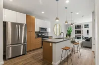 Sugarmont Kitchen and Living Room Modern open-concept kitchen with sleek stainless steel appliances, stylish pendant lighting, and a cozy living area with large windows at Sugarmont Apartments.