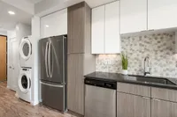 Sugarmont Kitchen Modern kitchen at Sugarmont Apartments with stylish stainless steel appliances, elegant wood cabinetry, and a chic geometric backsplash.
