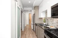 Sugarmont Kitchen Modern galley kitchen at Sugarmont Apartments featuring sleek stainless steel appliances, chic hexagon tile backsplash, and elegant sliding doors for a stylish touch.