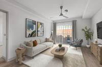 Modern living room with stylish beige sofa, colorful abstract art, and natural light streaming through large windows at Cottonwood Westside Apartments.