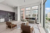 Contemporary open-plan apartment at Cottonwood Westside featuring a sleek kitchen with stainless steel appliances and a bright living area with floor-to-ceiling windows offering urban views.