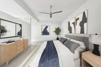 Elegant bedroom at Cottonwood Westside in Atlanta with modern decor, featuring a plush bed, stylish artwork, and a sleek ceiling fan.