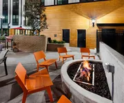 Inviting outdoor patio at Cottonwood Westside Apartments with modern orange chairs around a cozy fire pit, perfect for relaxed evening gatherings.