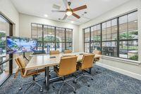 Bookable Private Conference Room Inviting conference room with modern furnishings, large windows offering natural light, and a wall-mounted screen for presentations at Apt CoWork at Toscana at Valley Ridge Apartments in Lewisville Texas