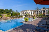 Poolside Lounge Areas Luxurious apartment complex, Heights at Meridian, with a sparkling outdoor pool, surrounded by stylish lounging chairs and lush greenery.