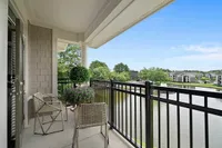 Balcony or Patio in Select Homes Elegant balcony at Heights at Meridian Apartments overlooking serene pond, featuring chic wicker chairs and vibrant green plants, perfect for relaxation.