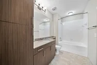 Bathroom with Oversized Vanity Elegant bathroom at Heights at Meridian Apartments with modern wooden cabinetry, granite countertops, and a sleek tub surrounded by white subway tiles.